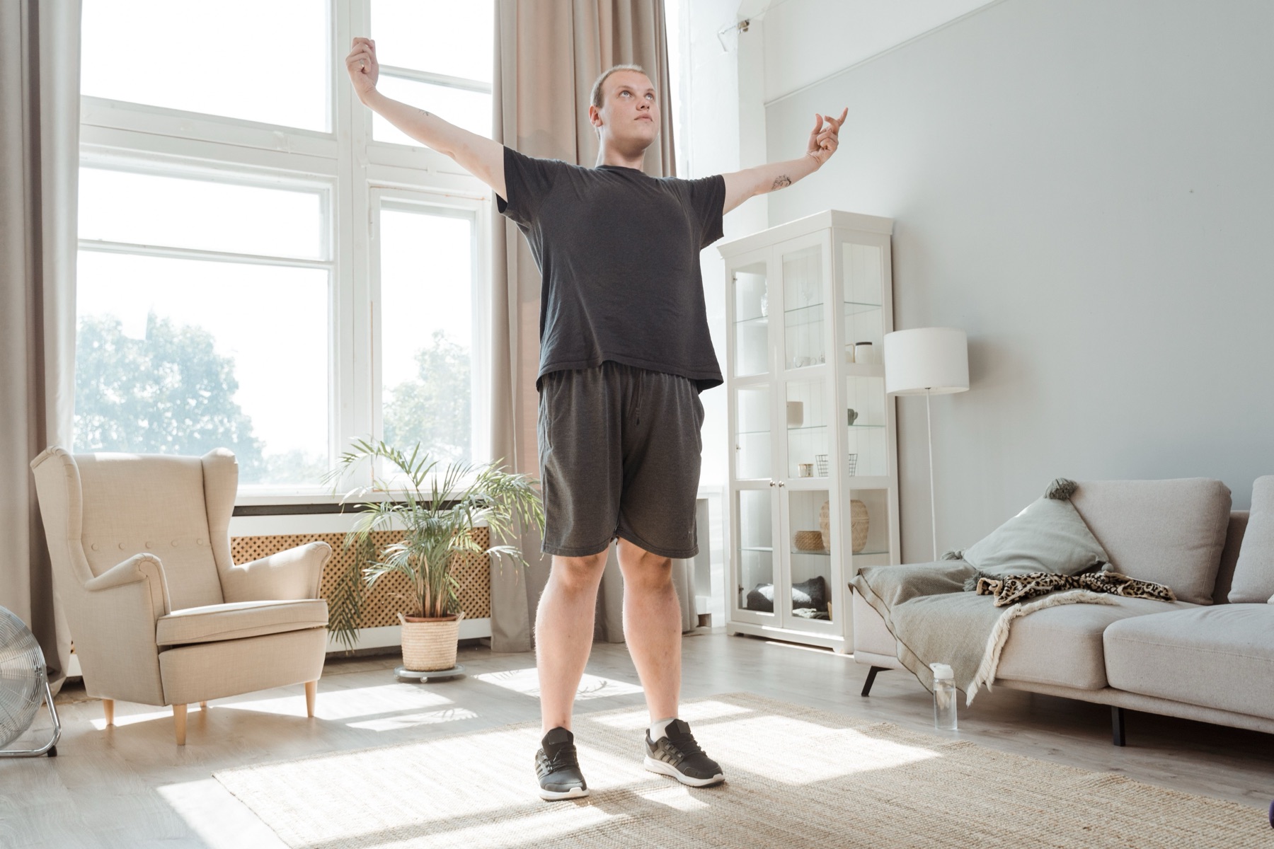 A patient mid-exercise at home, arms raised, with pose-tracking nodes overlaid